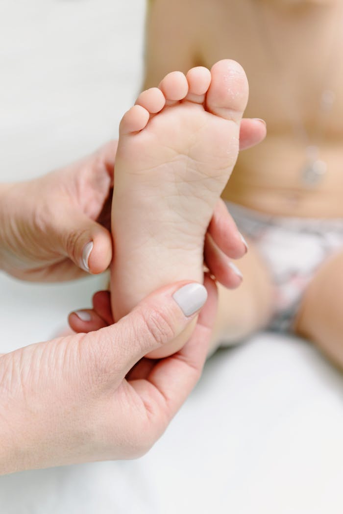 Gentle close-up of a baby's foot receiving massage therapy, promoting relaxation.